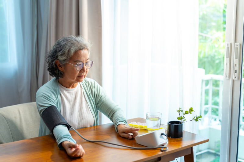 Older woman measuring her blood pressure at home, cocoa flavanols and heart health